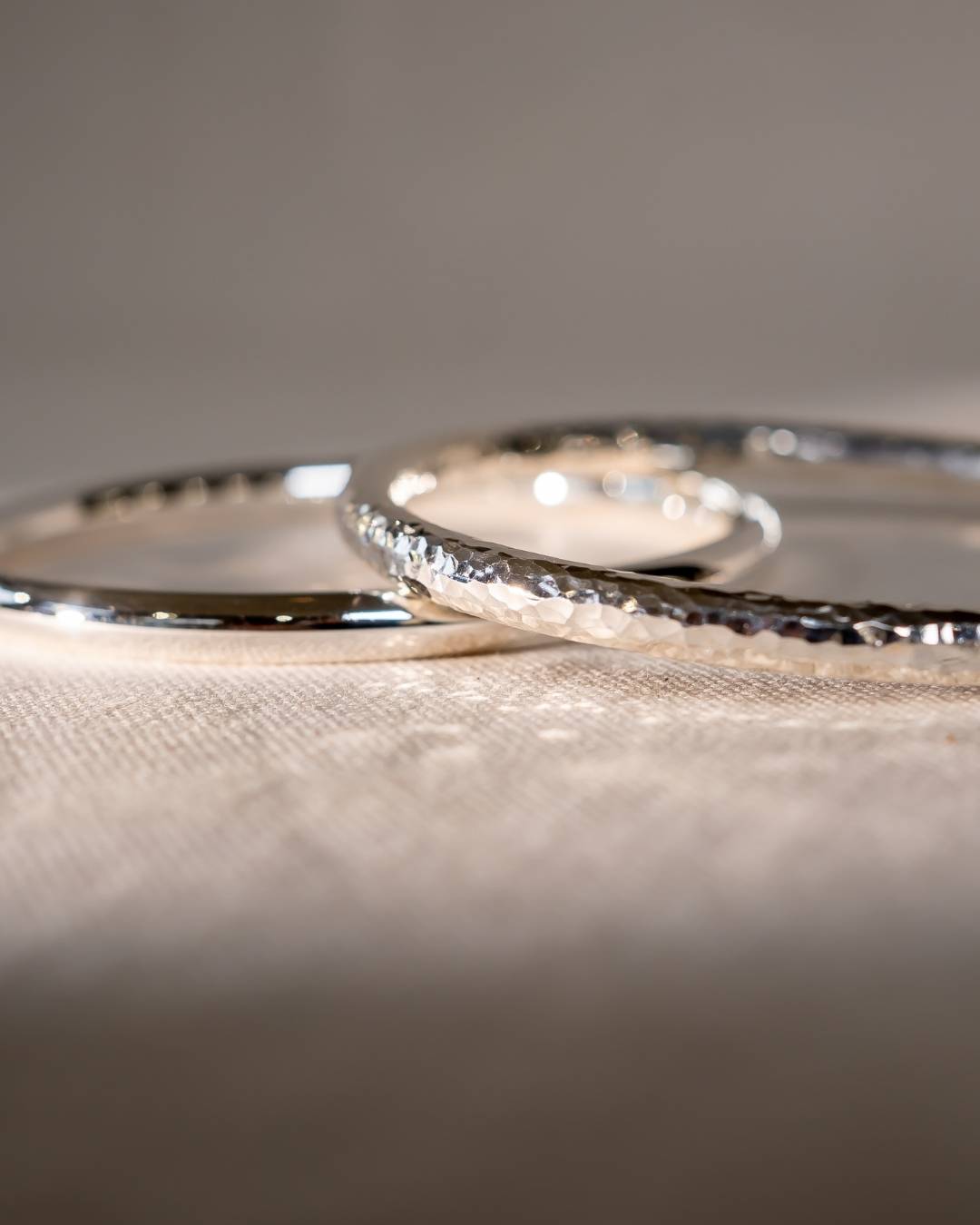 Handcrafted silver rings with hammered texture on a neutral fabric background