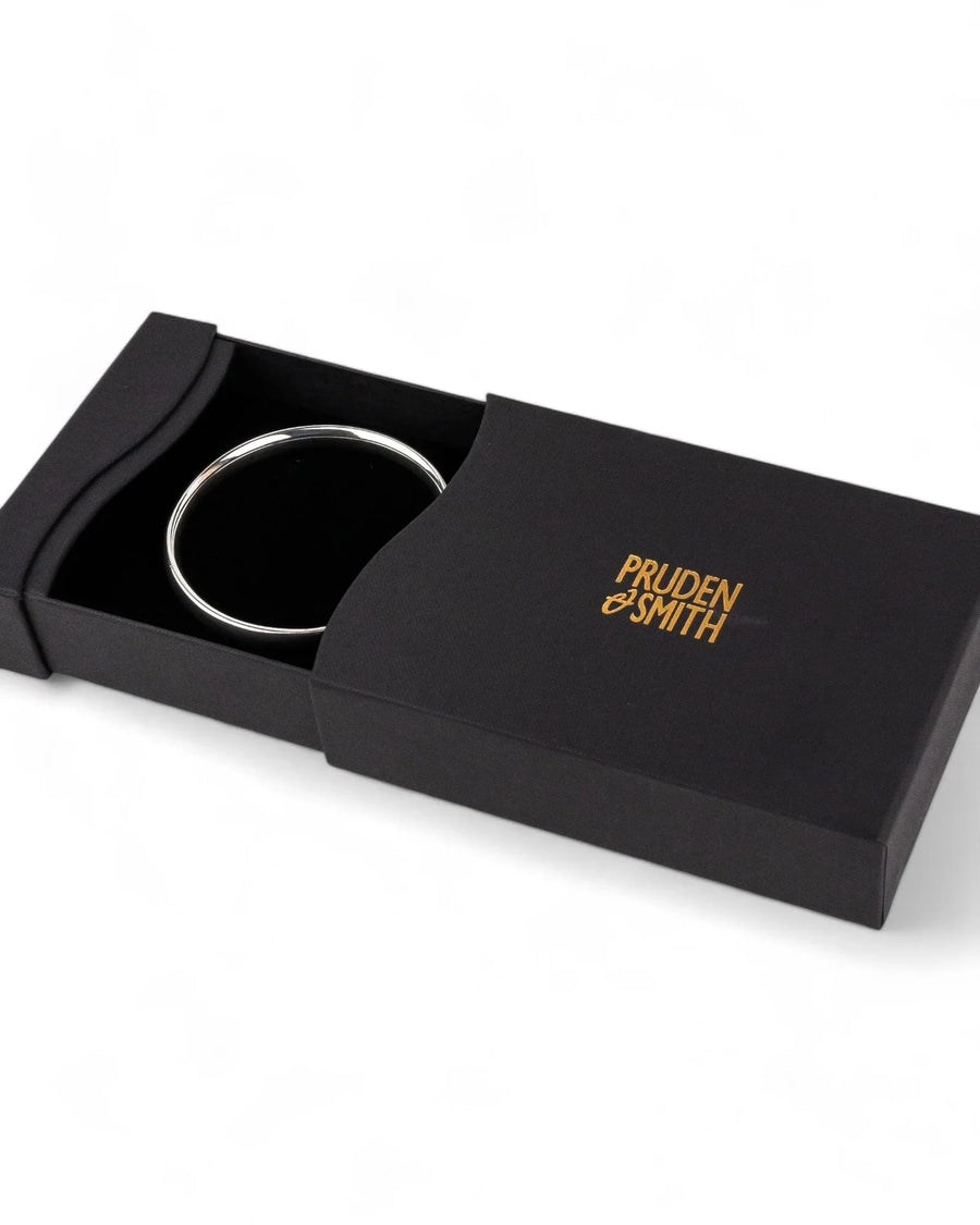 Silver bangle in a black gift box.