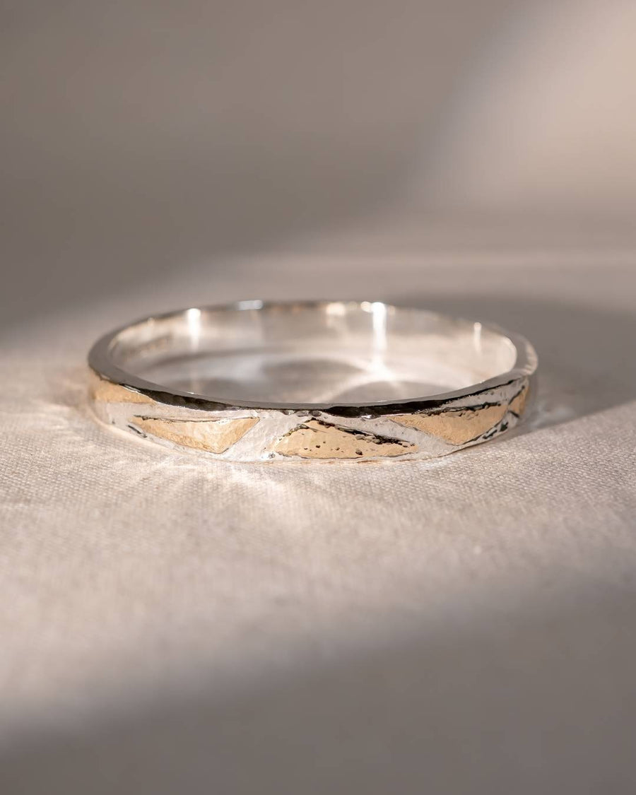Silver and gold hammered bangle with abstract design.