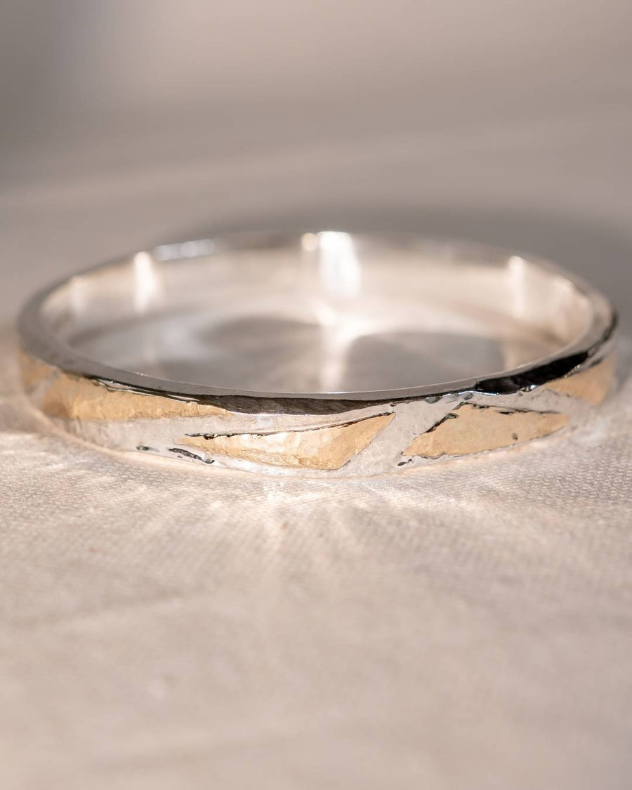 Silver and gold hammered bangle with an abstract design.