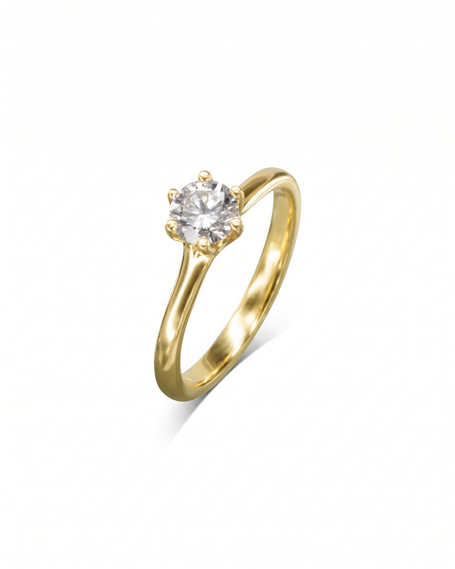 Gold solitaire engagement ring with a round diamond in a six-claw setting.
