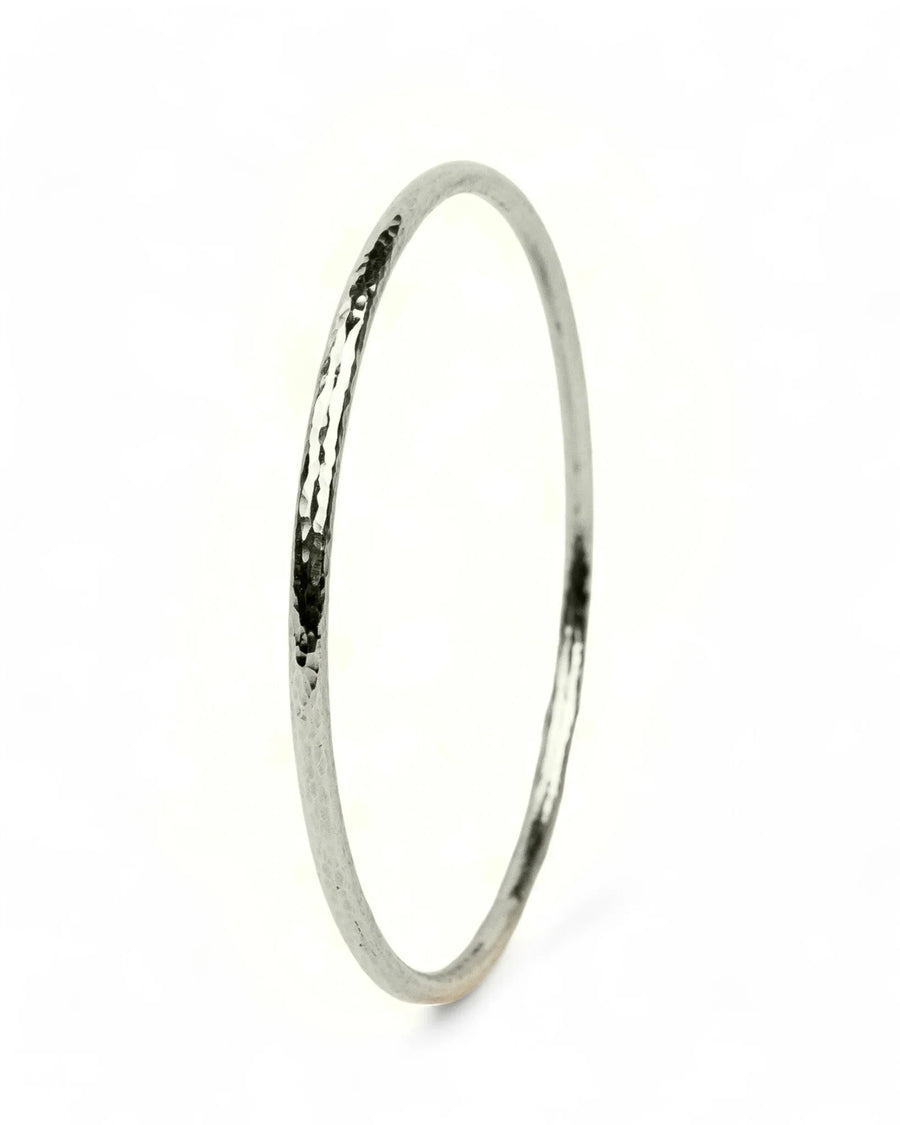 Handcrafted silver bangle with hammered texture on a white background, luxury jewellery