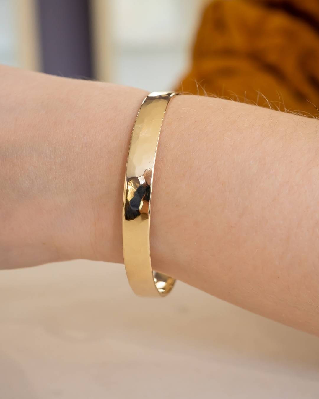 Handcrafted hammered gold bangle bracelet on wrist with natural finish, artisan jewelry