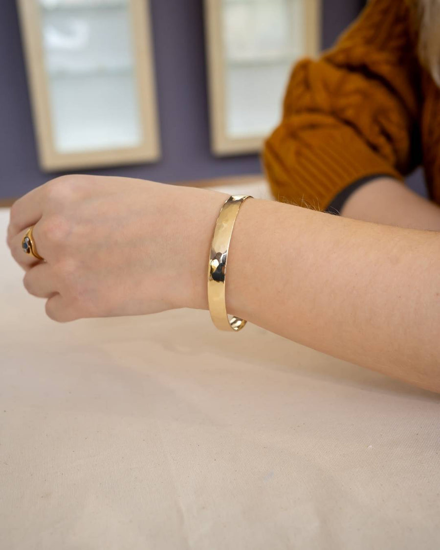 Handcrafted hammered gold bangle bracelet worn on wrist, artisan jewellery style