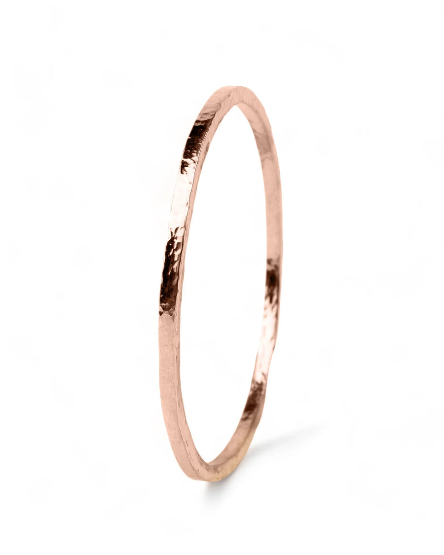 Handmade hammered rose gold bangle with organic texture on white background