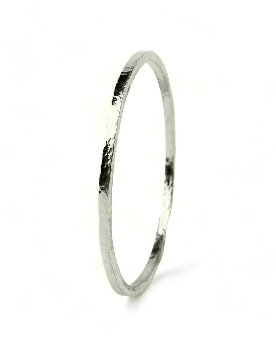Handmade silver bangle with hammered organic texture on white background
