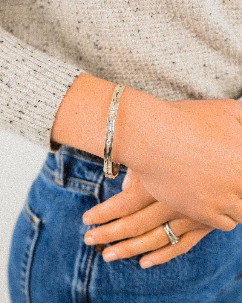 Solid silver and diamond bangle trap on a wrist.