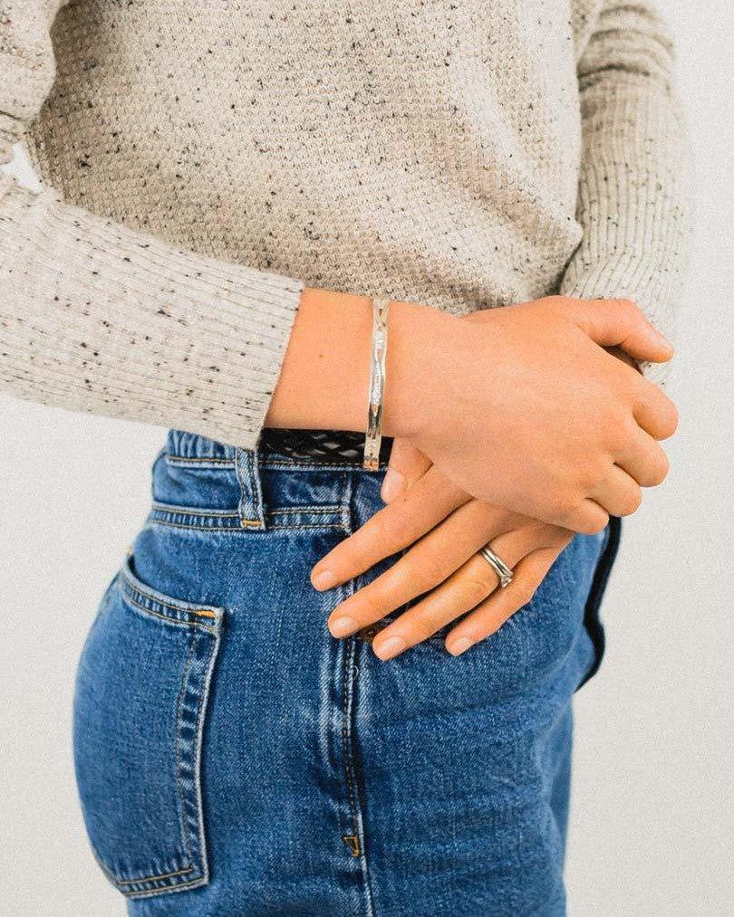 Solid silver and diamond bangle on a wrist, worn with a ring.