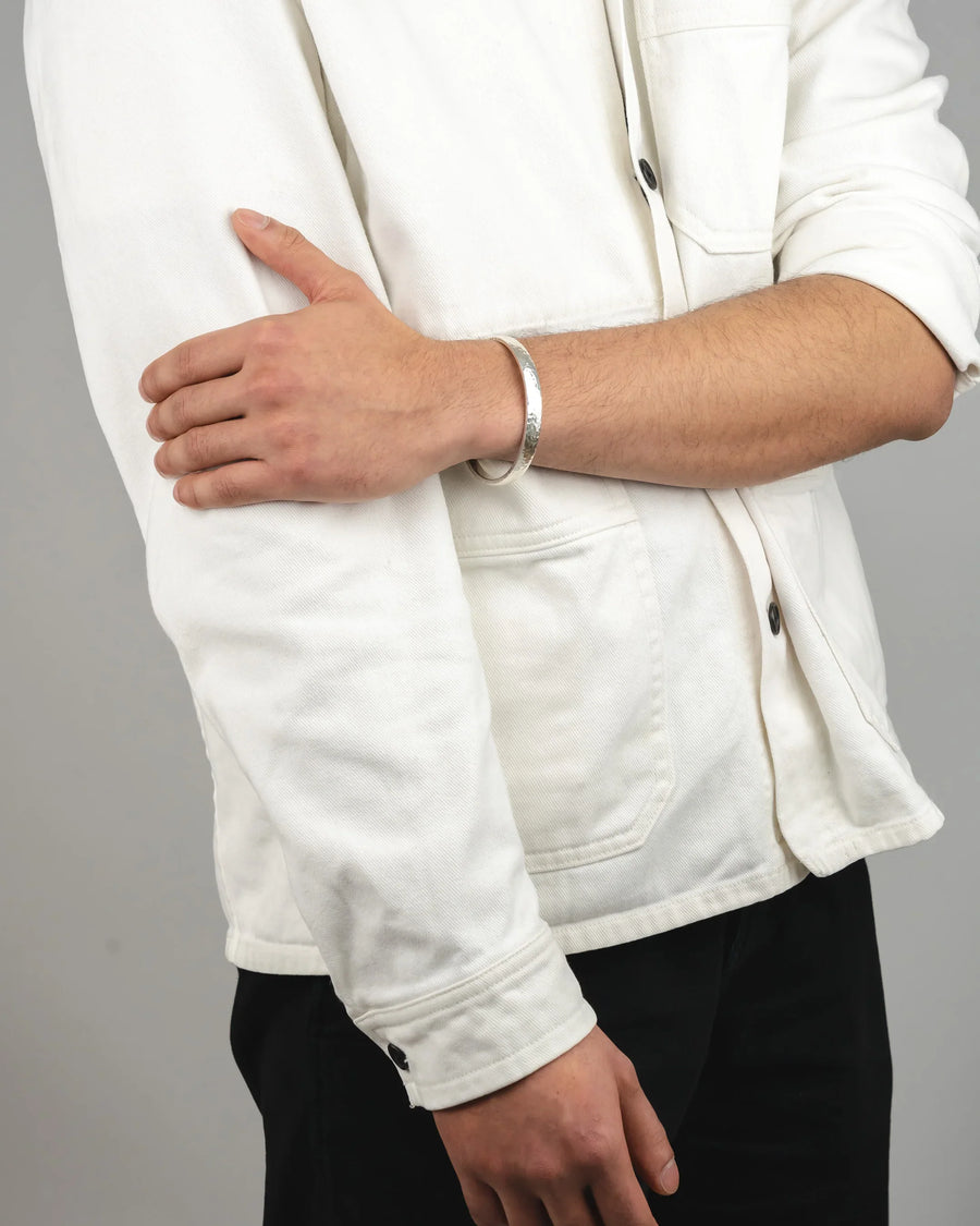 Handmade silver bangle on wrist, worn with white jacket and black trousers
