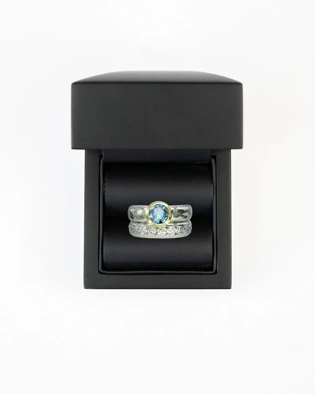 Two-tone aquamarine solitaire engagement ring with diamond band in black box