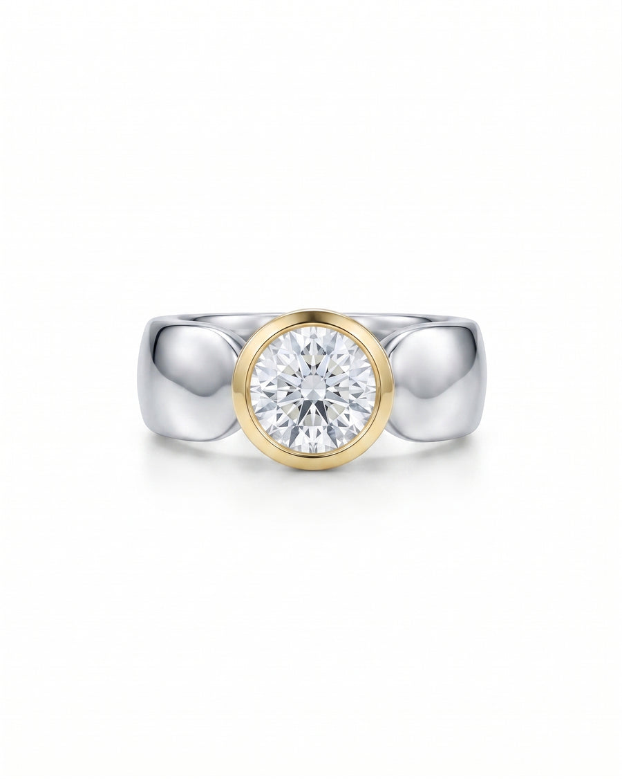 Two-tone engagement ring with a round solitaire diamond in a yellow gold bezel setting on a silver band.