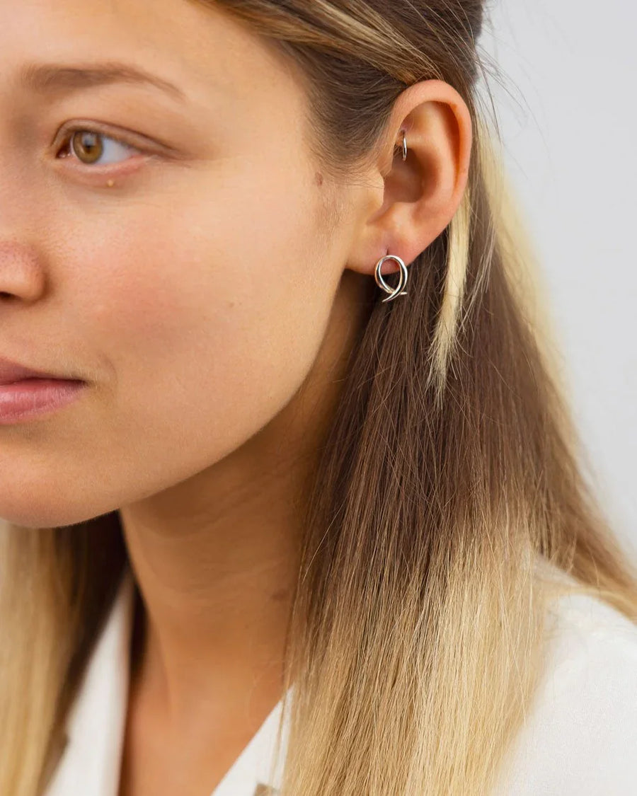 woman wearing unique silver spiky crossover stud earrings, modern handmade jewelry