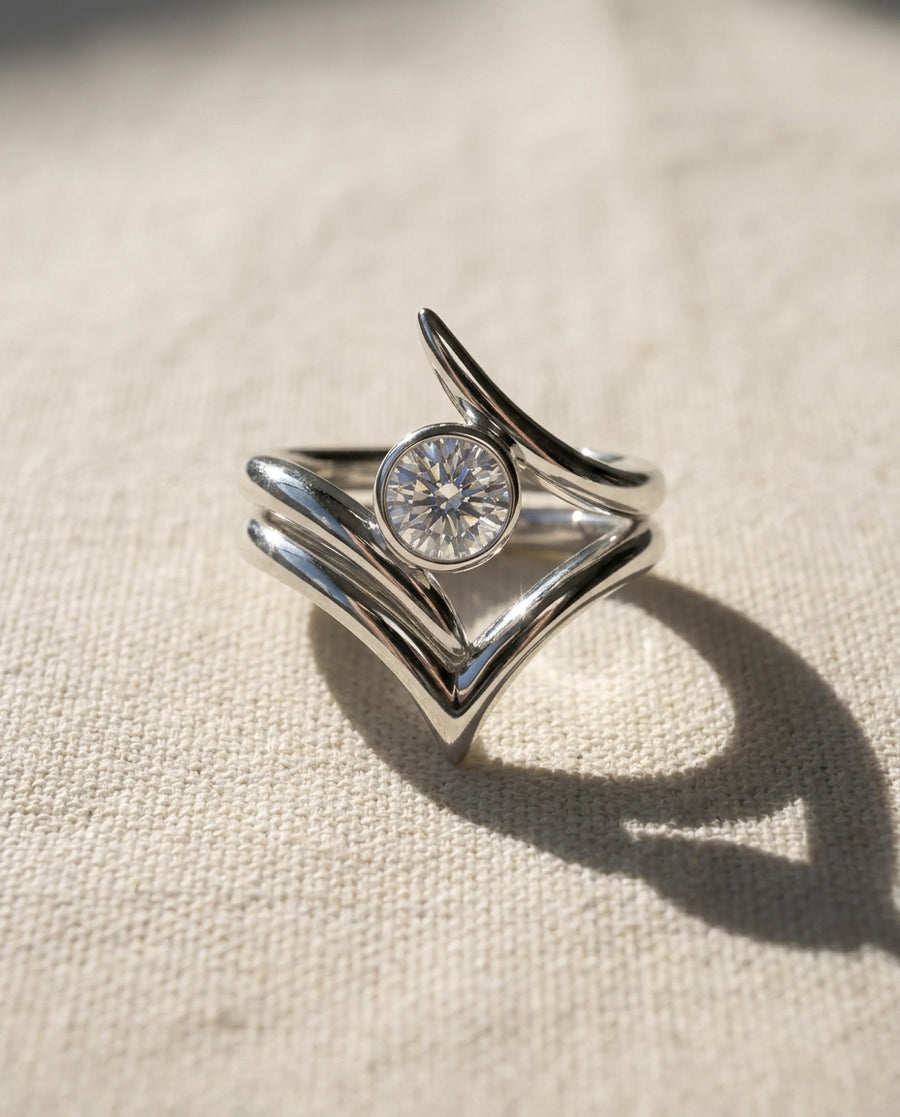 Silver spiky engagement ring with a round diamond and wishbone wedding band set.