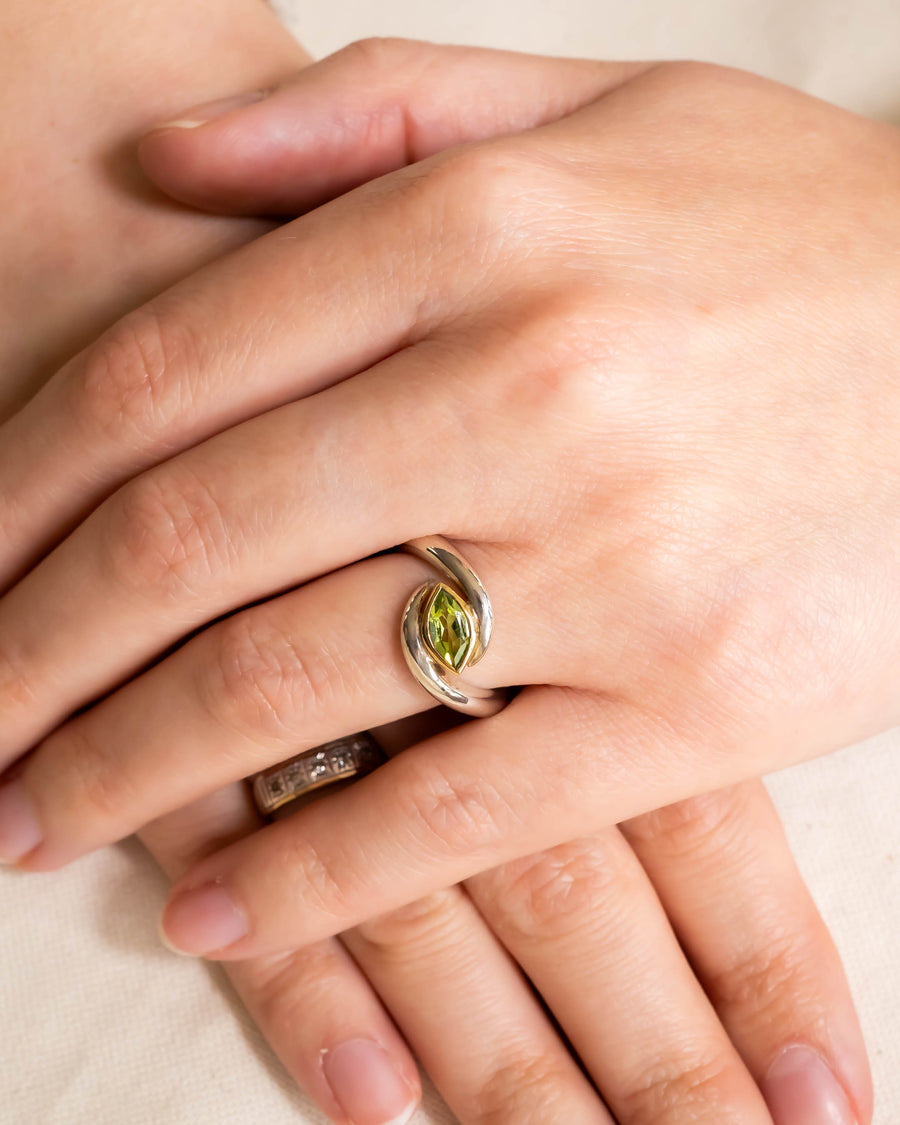 Silver and gold ring with a marquise-cut green peridot gemstone.