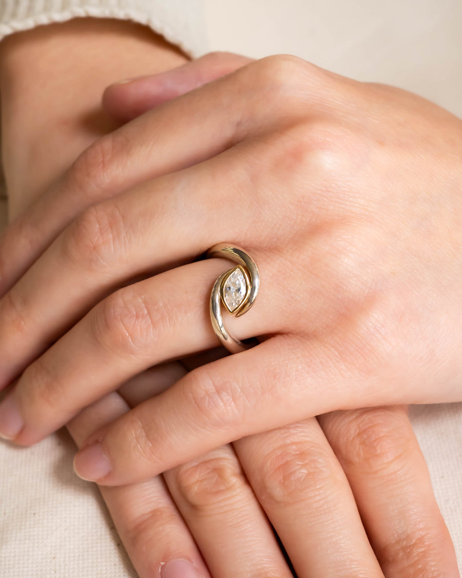 Gold ring with a marquise-cut diamond in a swirling bypass design.