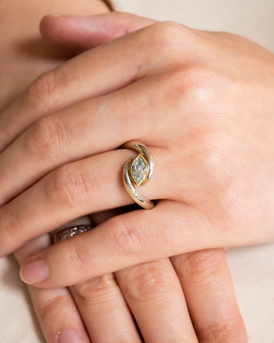 Silver and gold ring with a marquise-cut light green gemstone.