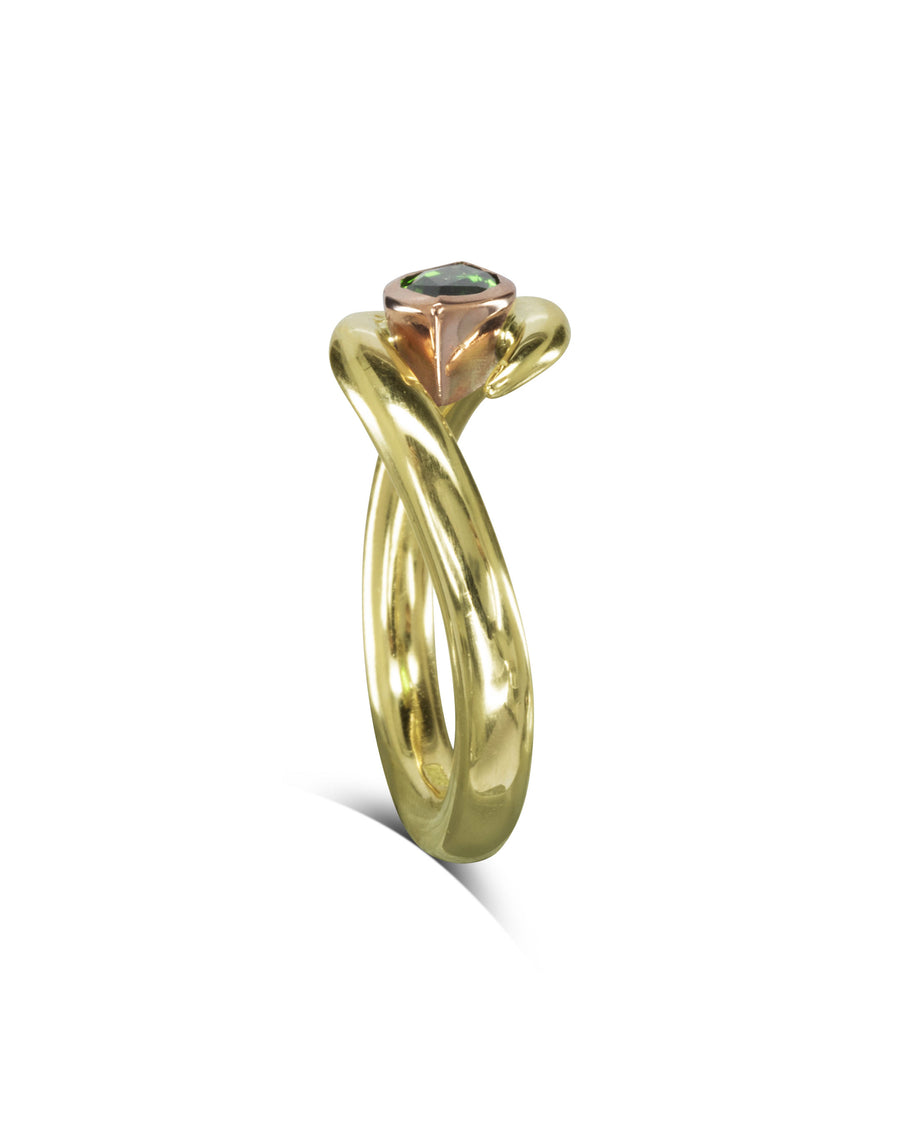 Gold stacking ring with a twisted band and a rose gold setting featuring a small green gemstone.