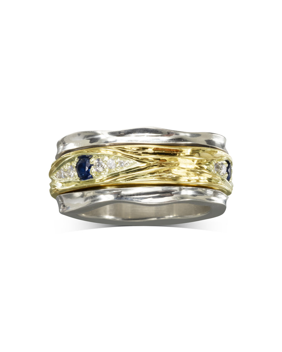Two-tone gold and silver ring with blue and white gemstones.