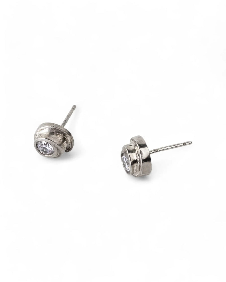 Silver stud earrings with a round diamond in a bezel setting.
