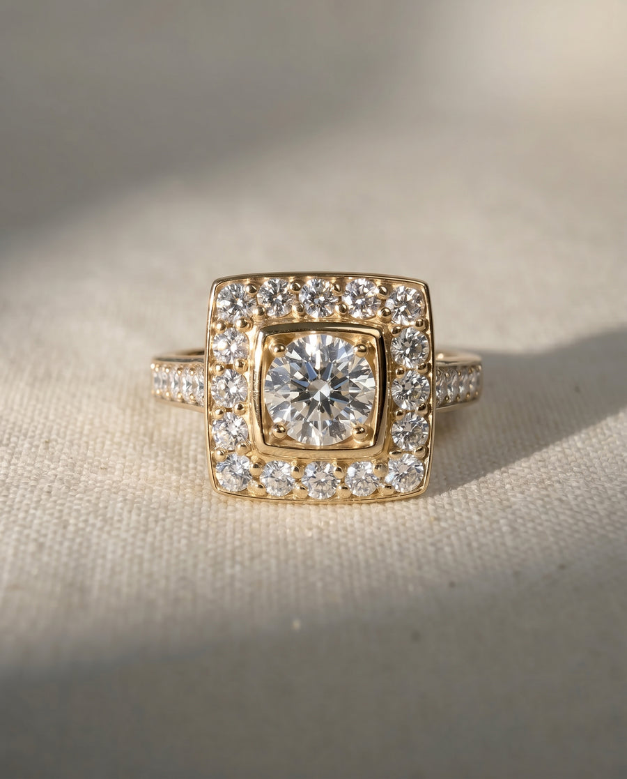 18ct yellow gold square cluster engagement ring with a round natural diamond center and diamond shoulders.