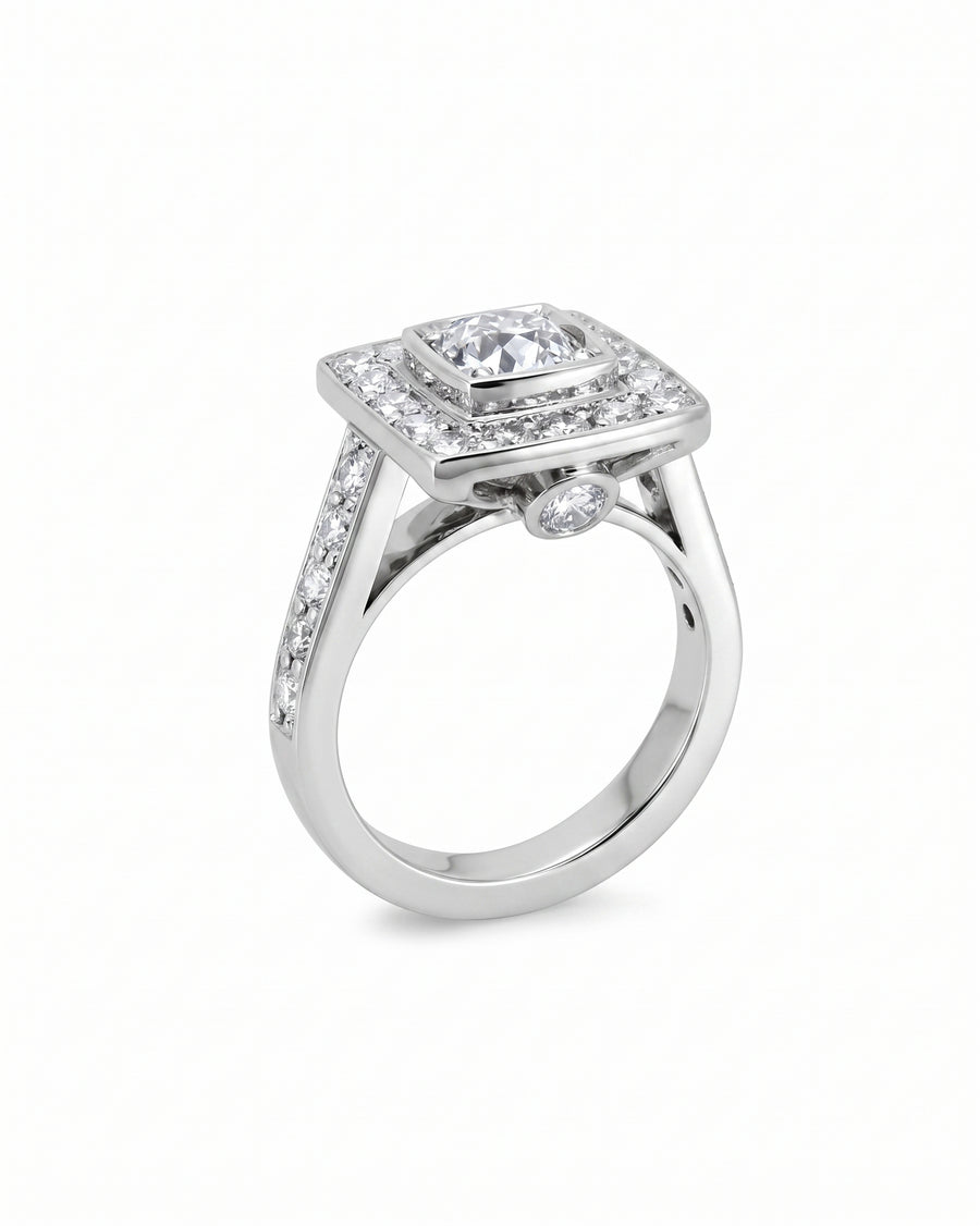 White gold square cluster engagement ring with diamond shoulders.