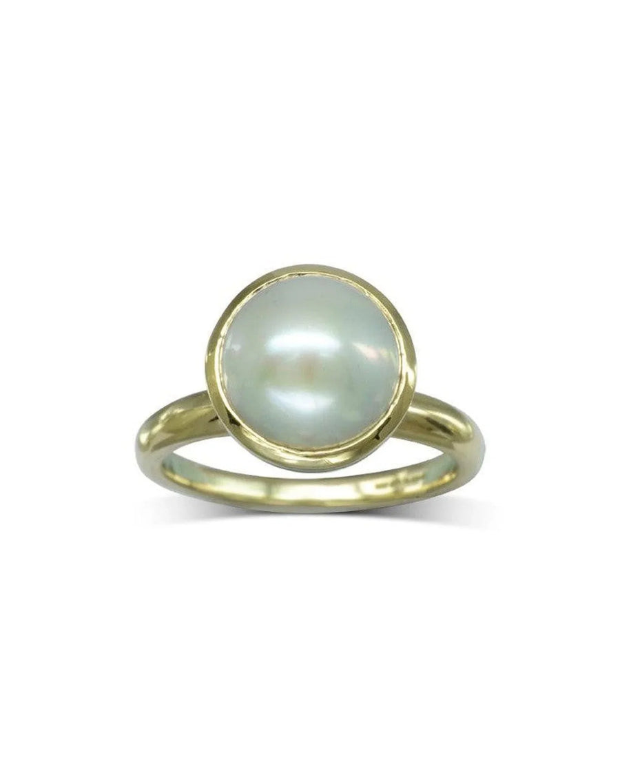 Gold ring with a large, round white pearl in a bezel setting.