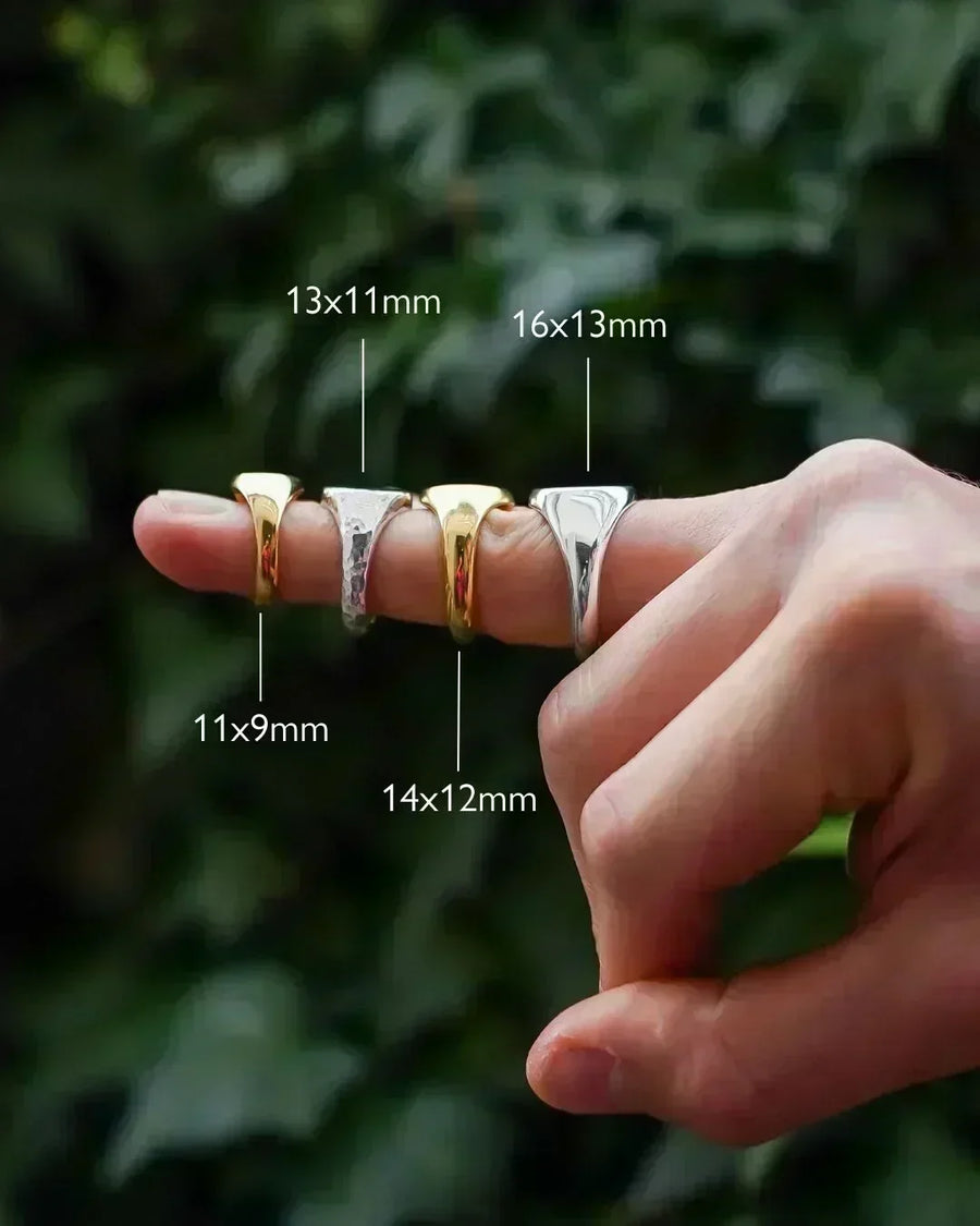 Hand modeling four signet rings in gold and silver, each labeled with their sizes