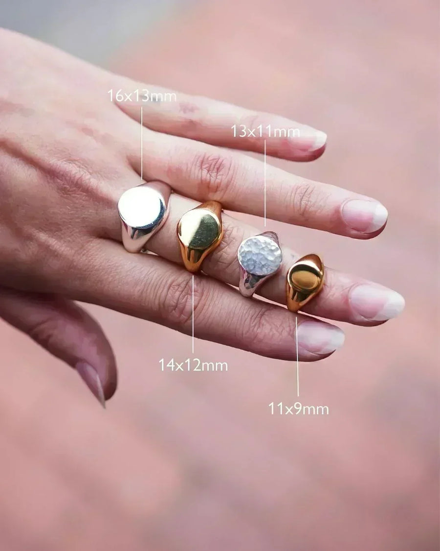 Hand wearing four signet rings in silver and gold, with size measurements shown.
