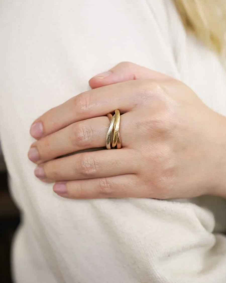 Hand wearing an intertwined gold Russian ring with organic, textured design