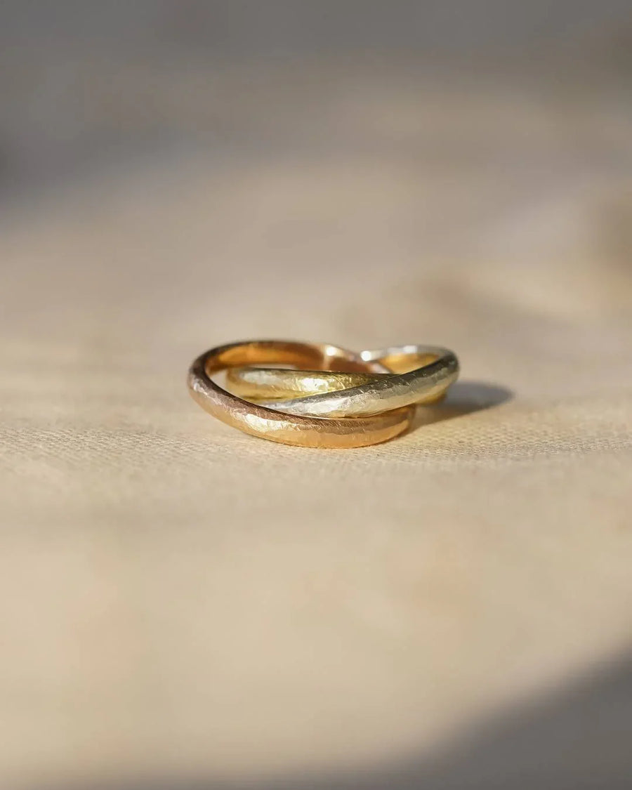 Handmade Russian ring with interlocking gold, silver, and rose gold bands on a neutral fabric
