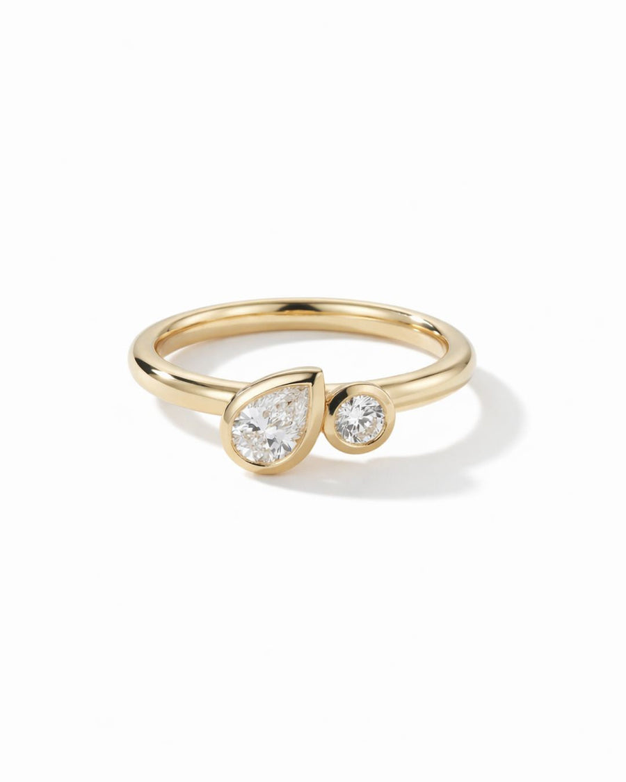 Gold toi et moi engagement ring with bezel-set pear and round diamonds on a polished yellow gold band.