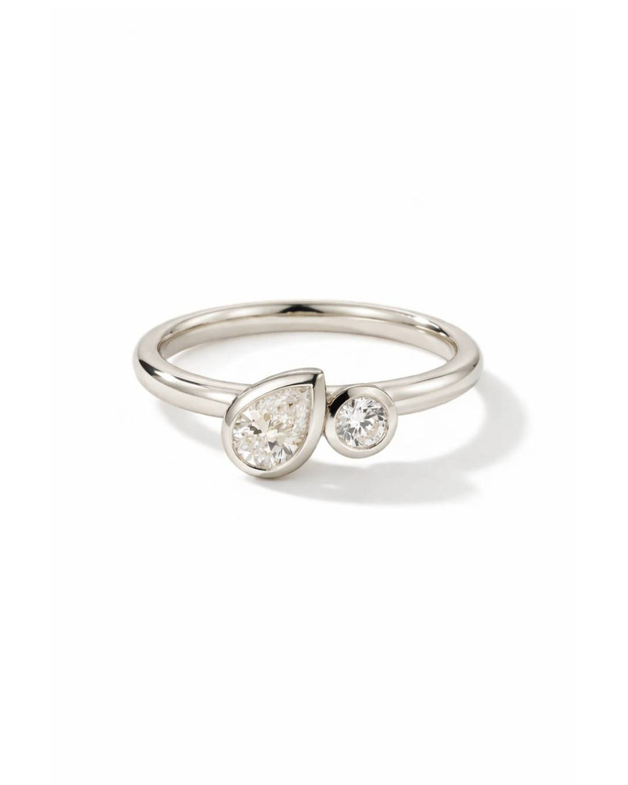Toi et moi engagement ring in silver metal with a bezel-set pear diamond and a round diamond.