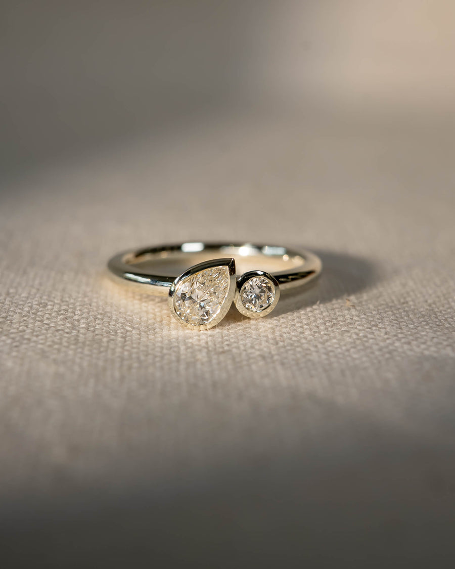 Platinum toi et moi engagement ring with bezel-set pear and round lab grown diamonds.