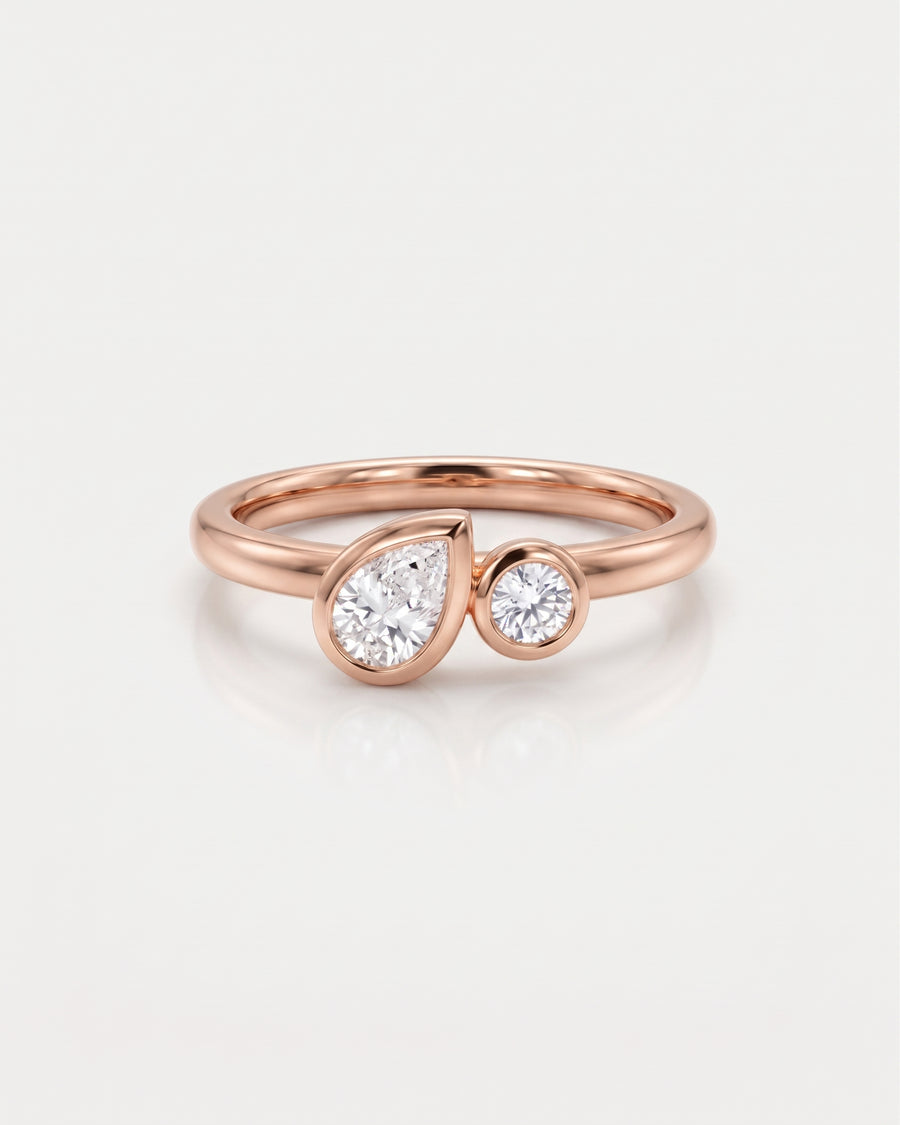 18ct rose gold toi et moi engagement ring with a bezel-set pear and round lab grown diamond.