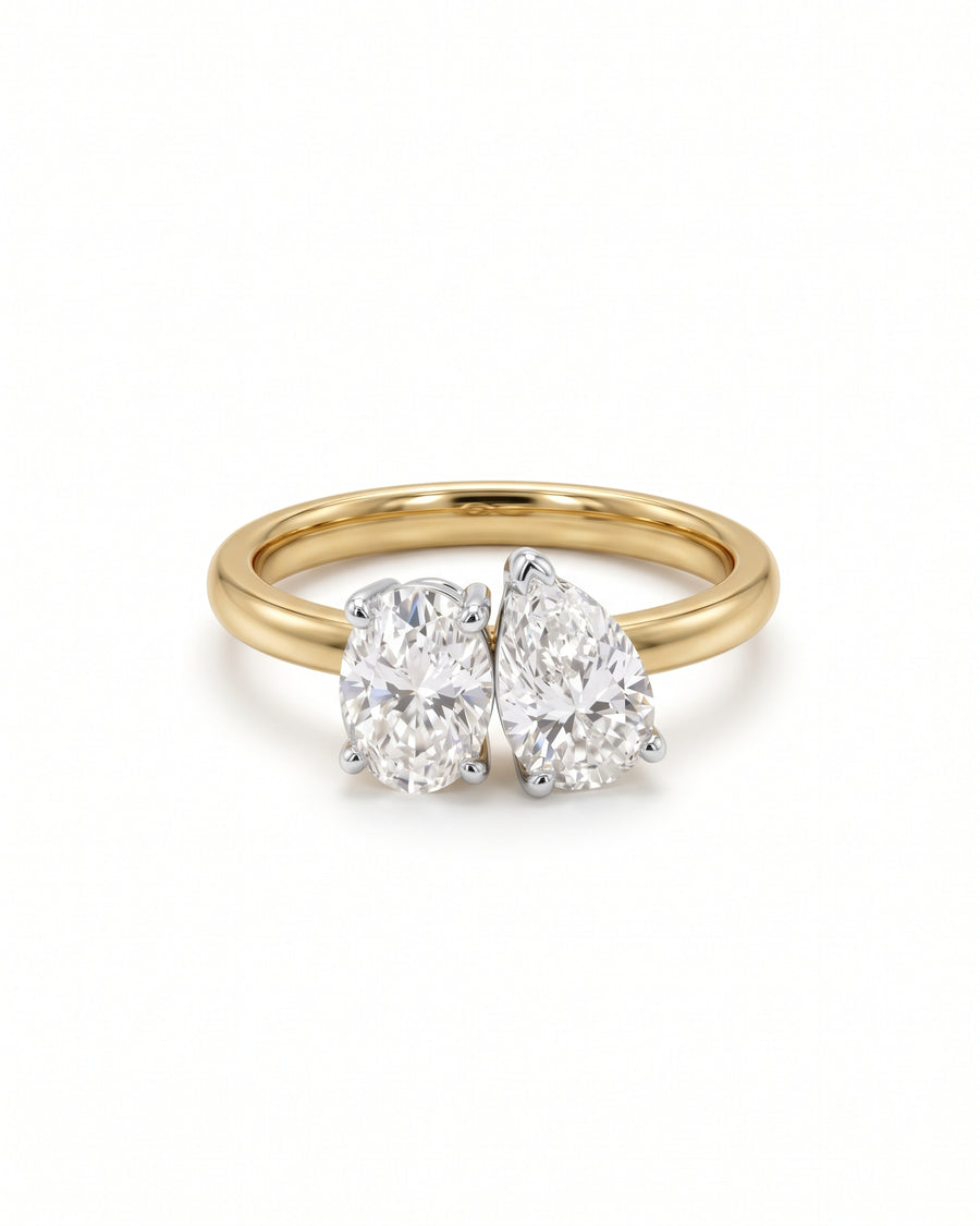 Gold toi et moi ring featuring an oval and a pear-cut diamond in claw settings.