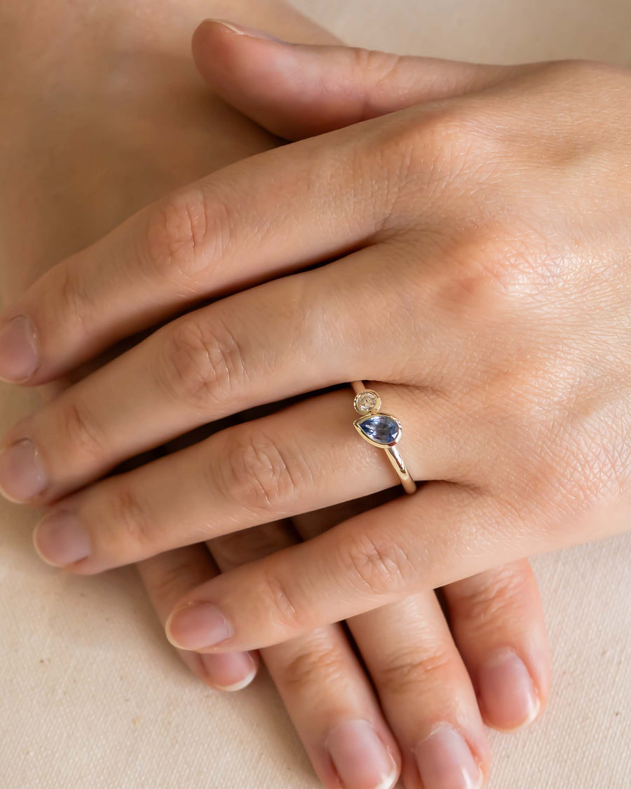 Gold Toi et Moi ring with a pear-shaped blue sapphire and a round white diamond.