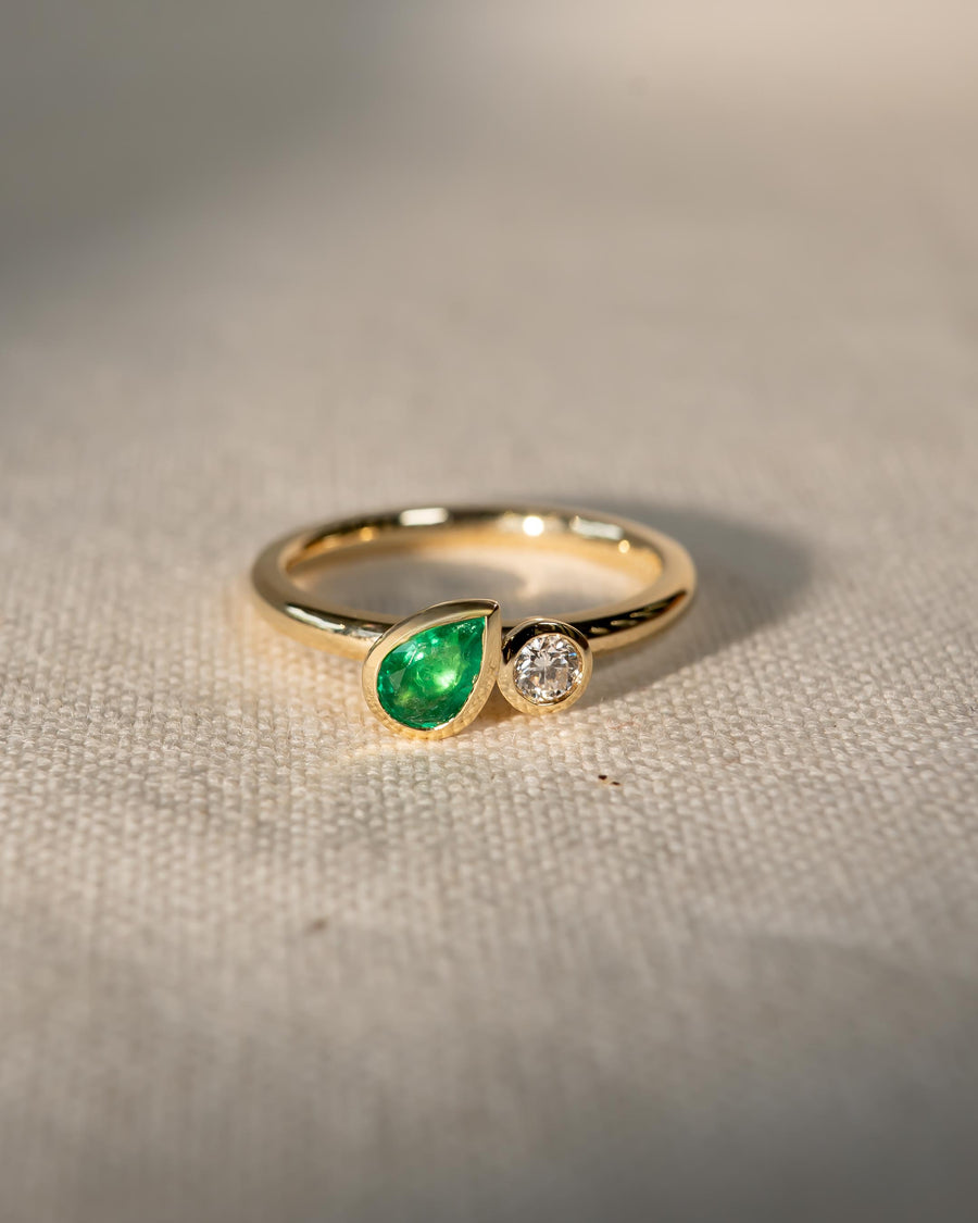 9ct yellow gold ring with a pear-cut emerald and a round diamond.