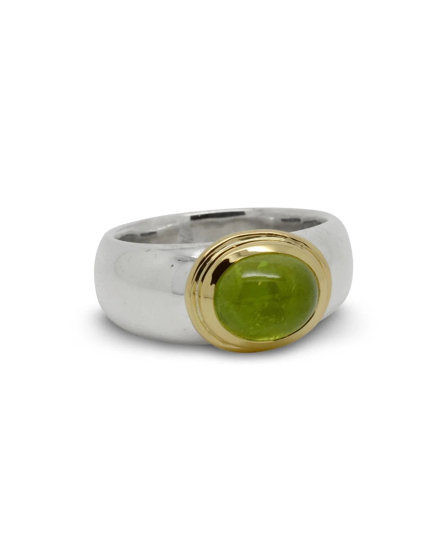 Silver band ring featuring an oval green peridot cabochon in a yellow gold bezel setting.
