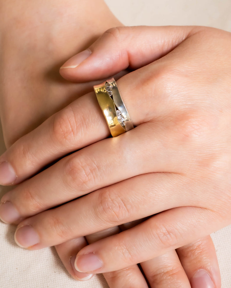 Wide gold and silver eternity ring with trap diamonds on a hand.