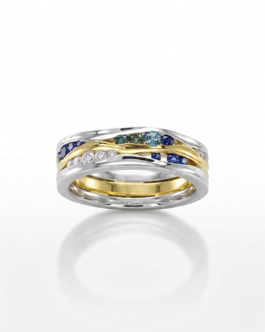 Gold and silver eternity ring with green, blue sapphire, and diamond gemstones.