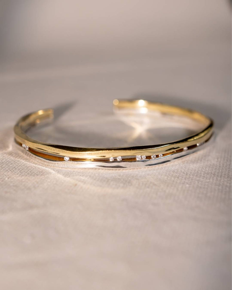 Handmade gold bangle with small diamonds, organic shape, luxury jewellery on fabric background
