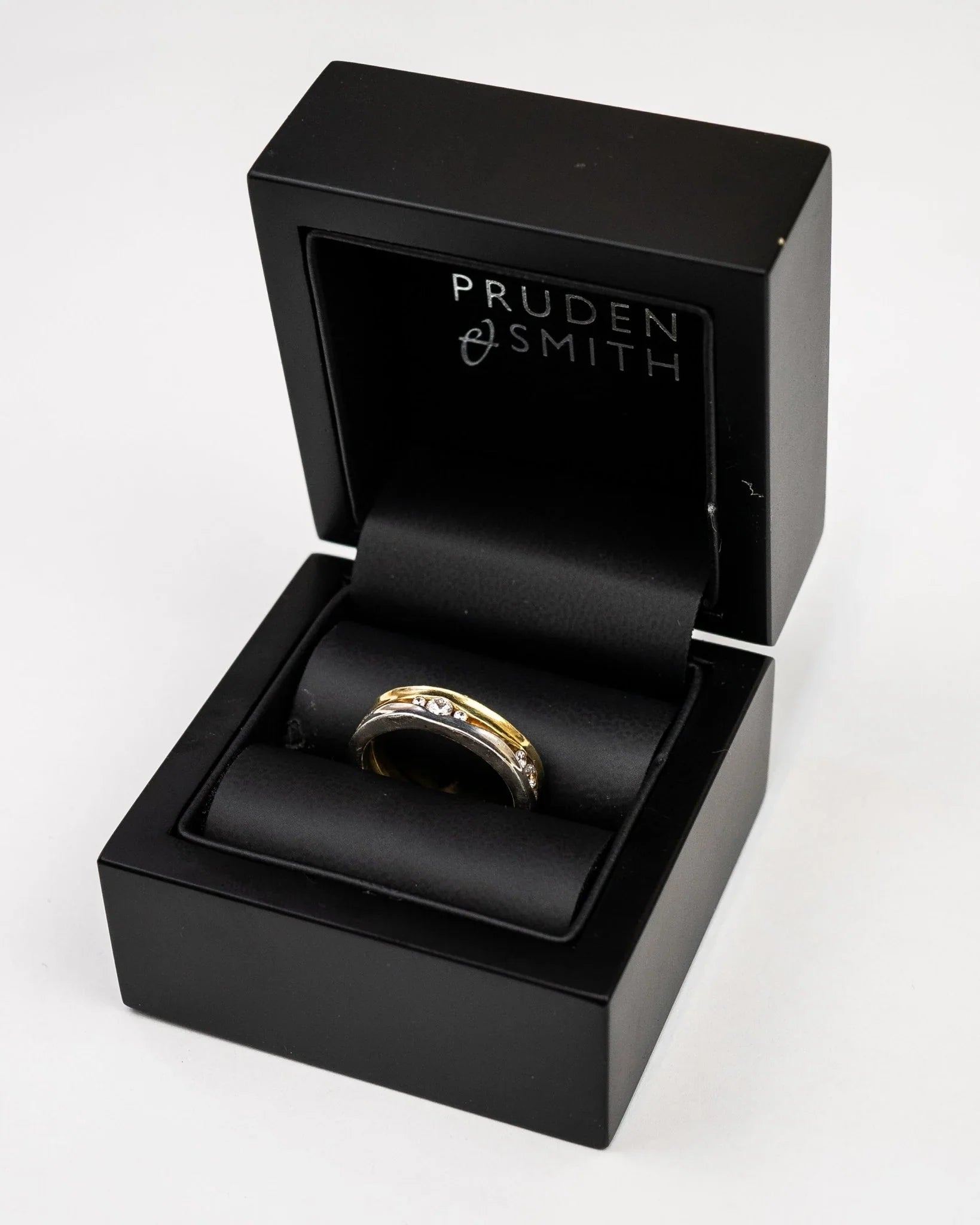 Eternity ring with pink sapphires and hammered gold band in black jewelry box