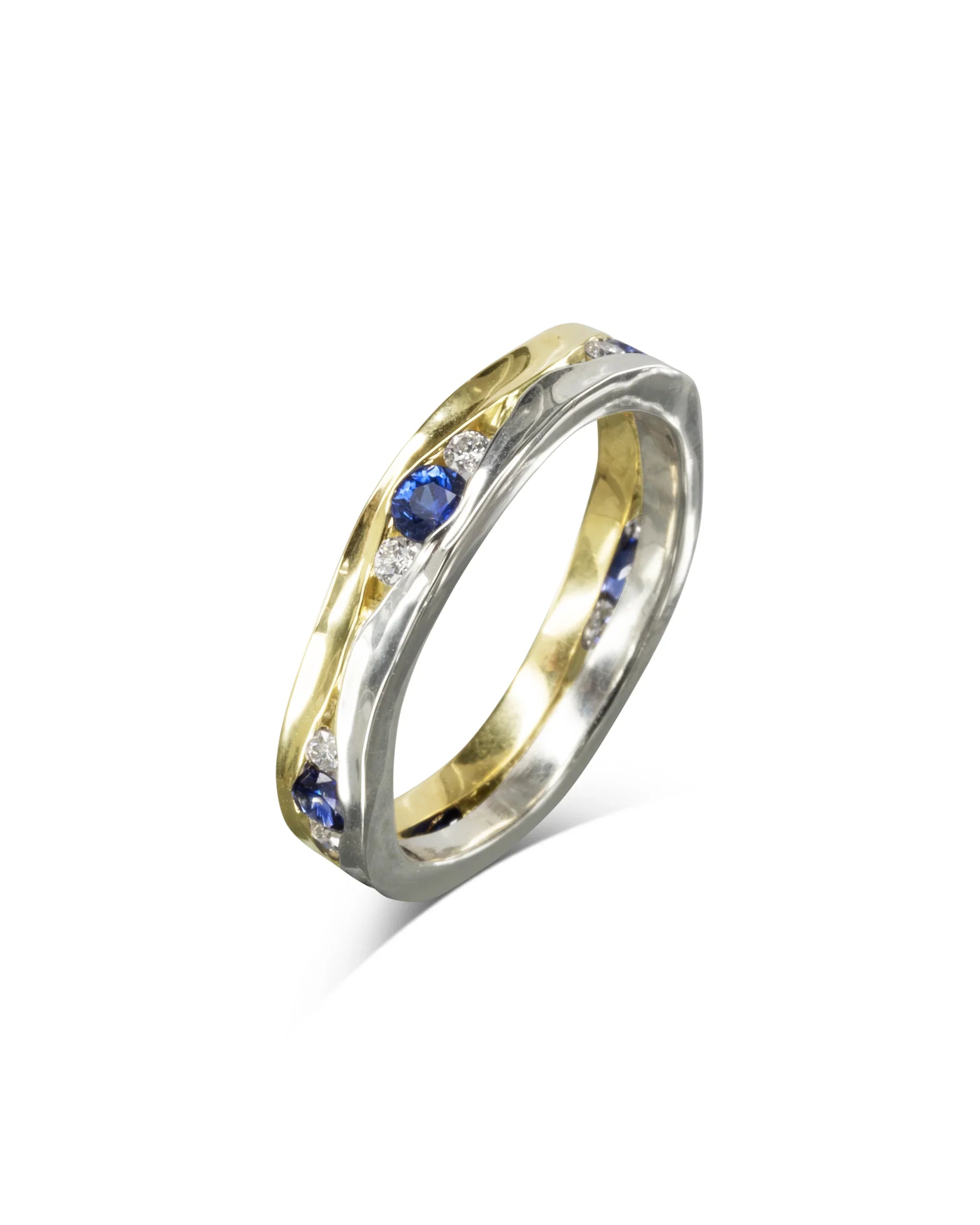 Narrow gold and silver eternity ring with blue sapphires and white diamonds on white background