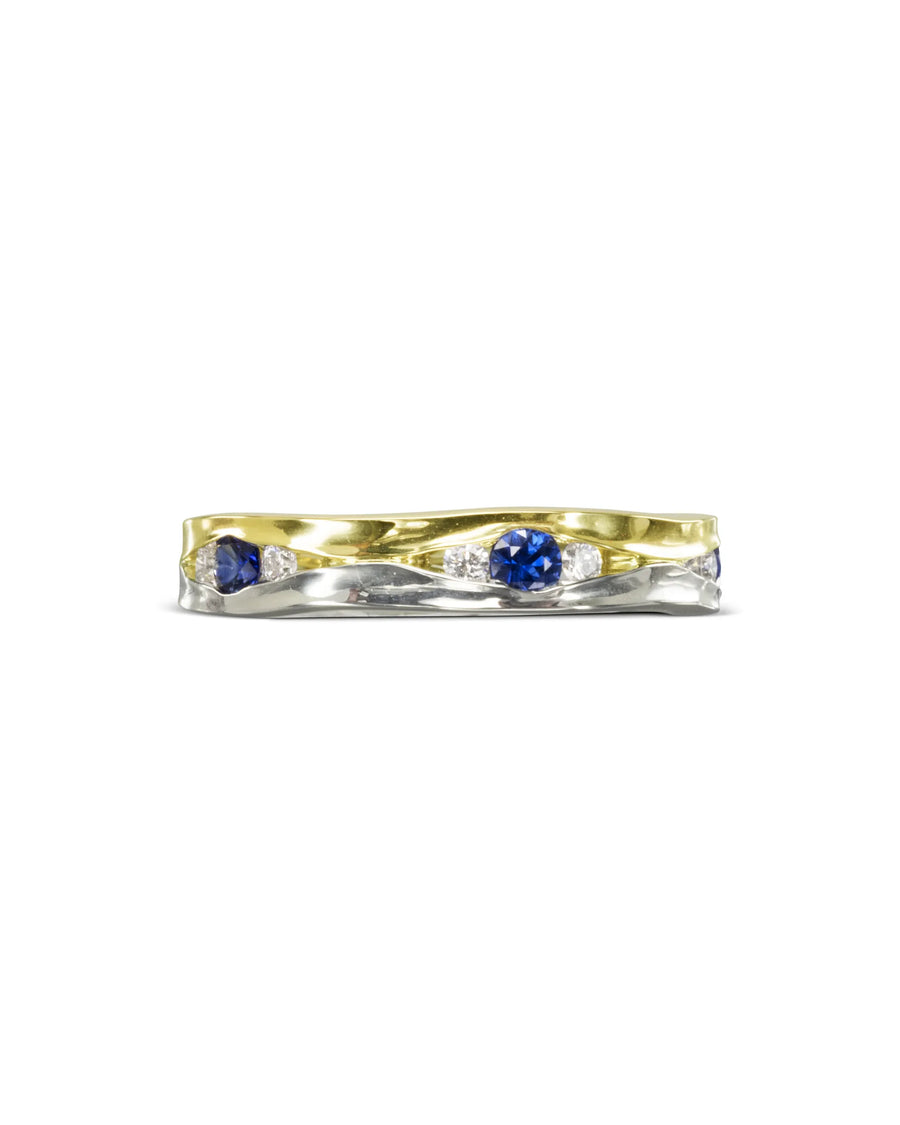 Two-tone gold eternity ring with round blue sapphires and small diamonds.