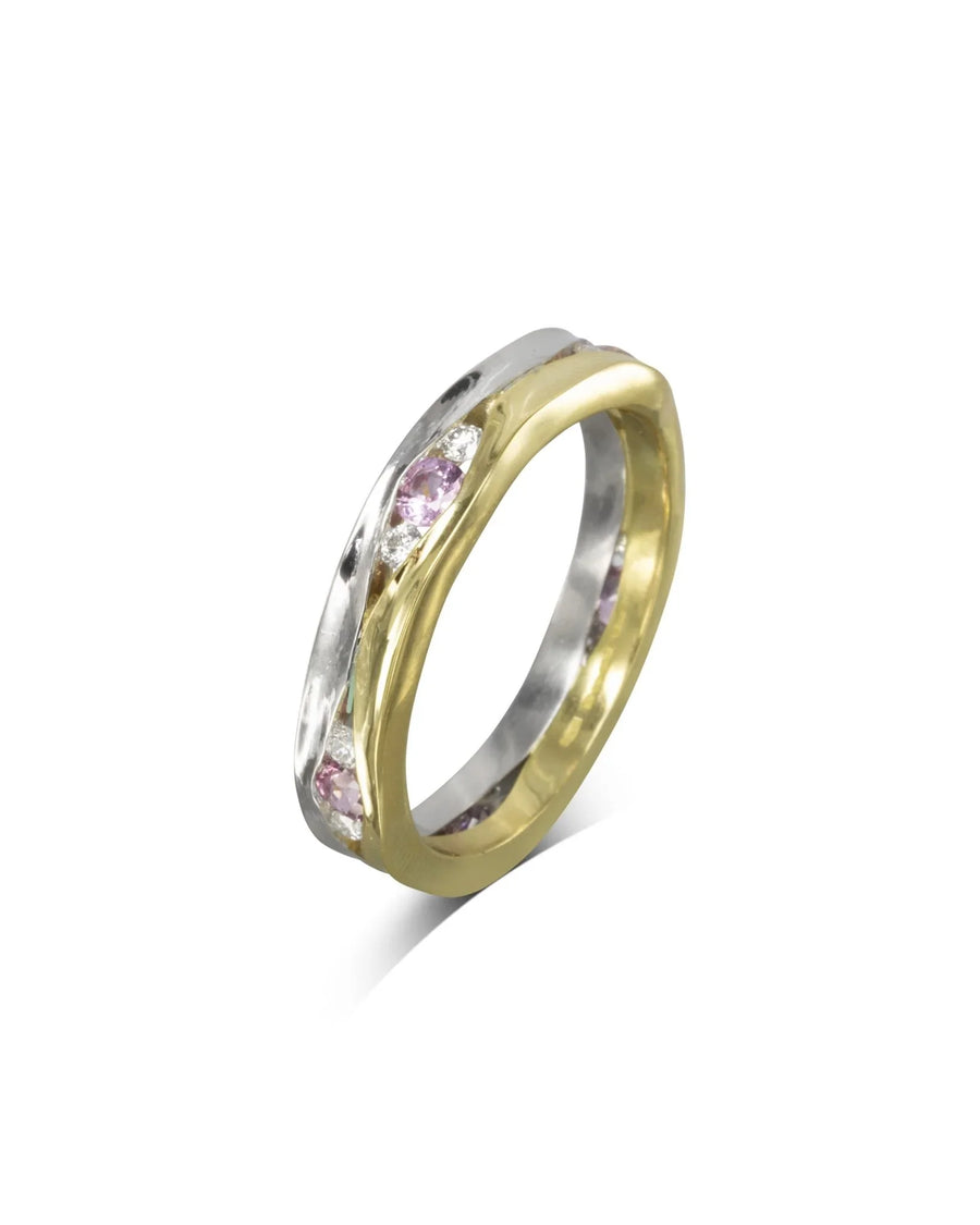 Two-tone gold eternity ring with trap-cut pink sapphires and diamonds.