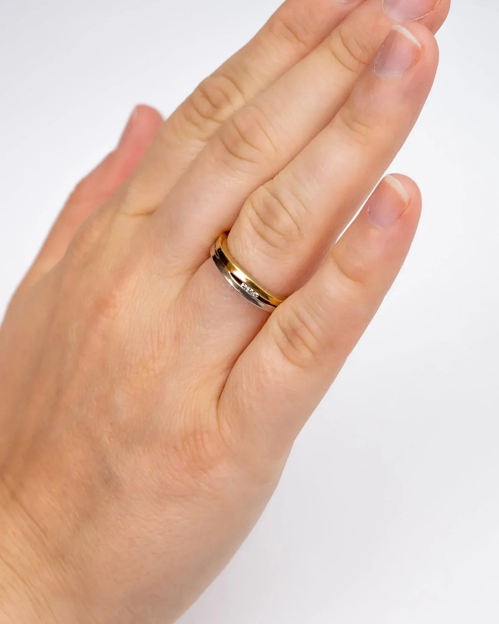 Hand wearing a two-tone gold and platinum diamond eternity ring