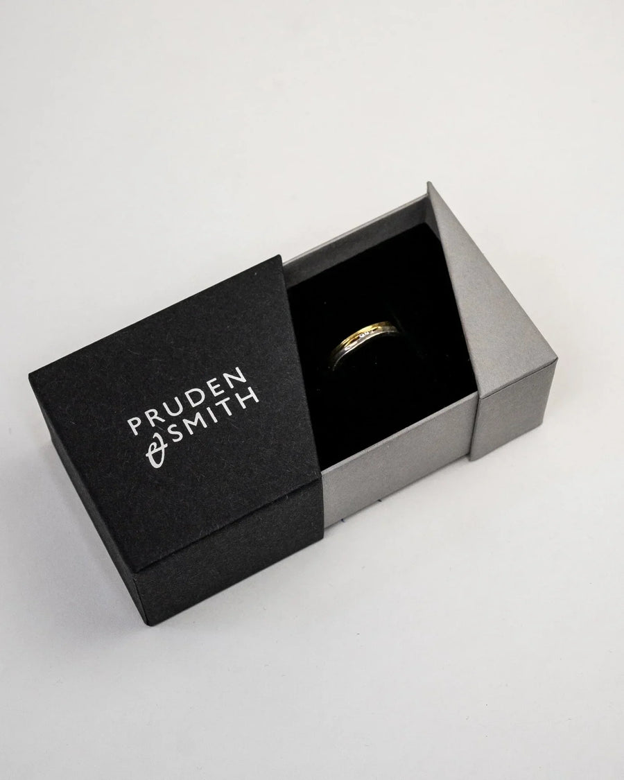 Gold trap textured two-colour diamond ring in a black and grey box.