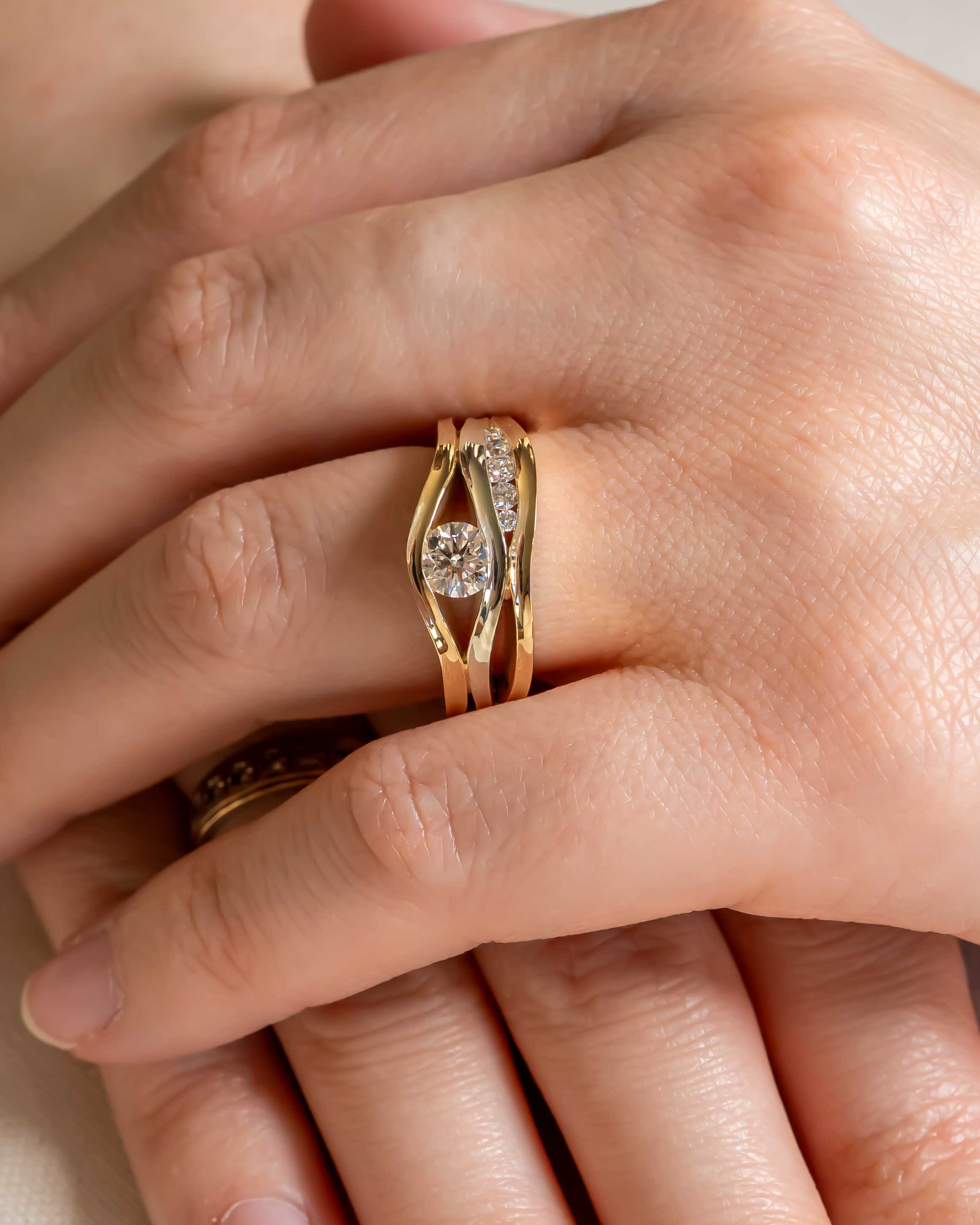 Gold three-band ring with a round diamond center stone and pavé diamonds.