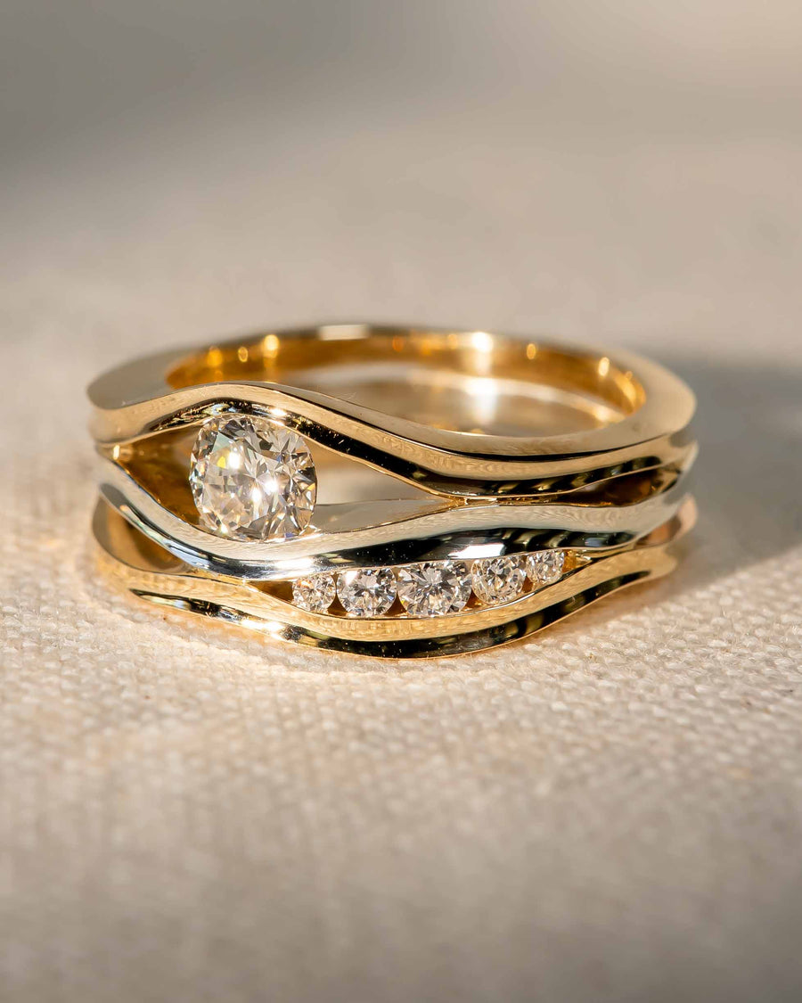 Gold and silver three-band diamond ring with a large center diamond and five smaller diamonds.