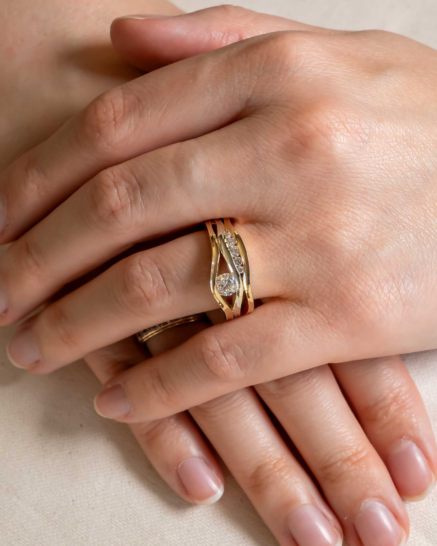 Gold three-band diamond ring with a central round diamond and accent diamonds.